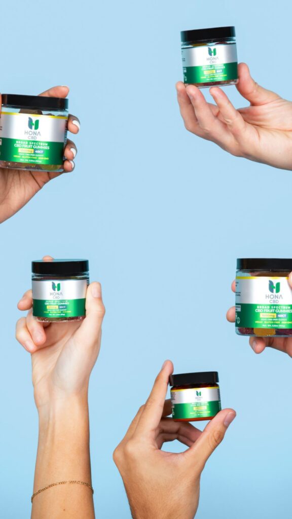 Hands Holding and Displaying Different HONA CBD Products. 